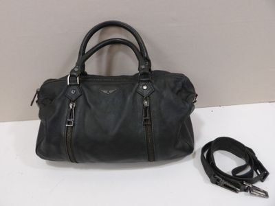 black leather handbag with zippers and a leash on a white surface