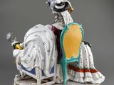 figurine of a lady sitting on a bed with a baby in a crib