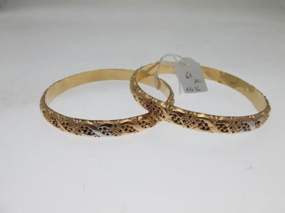two gold tone bang bracelets on a white surface