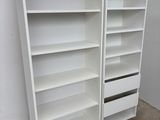 Deux bibliothèques blanches sont empilées sur des palettes dans un entrepôt