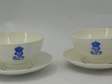 two cups and saucers with blue designs on them