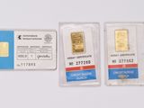 two gold bars are sitting next to each other on a white surface