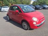 red fiat car parked in a parking lot with other cars in the background