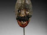 un masque en bois avec une barbe et une moustache, posé sur un socle