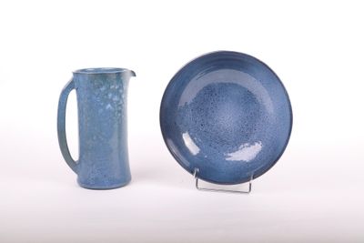 une assiette bleue et un pichet bleu posés l'un à côté de l'autre