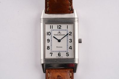 une montre en argent avec un bracelet en cuir marron sur un fond blanc