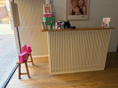 une photo d'un salon de coiffure avec un fauteuil rose devant