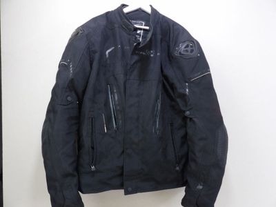 une veste de moto noire suspendue à un cintre sur un mur blanc