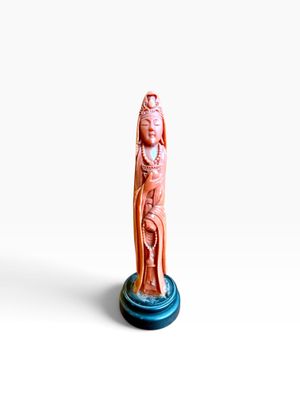figurine représentant une femme tenant un bébé dans ses bras, posée sur un socle bleu