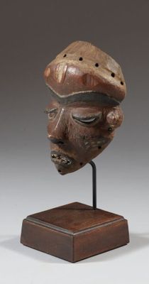 une photo d'une sculpture en bois représentant le visage d'un homme, posée sur un socle