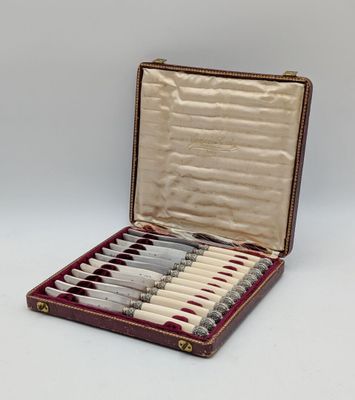 an open case with six knives in it sitting on a white surface