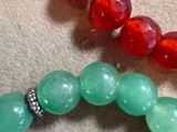 two bracelets with red and green beads on a table