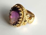 a close up of a gold ring with a purple stone