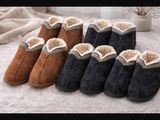 four pairs of slippers are lined up on a bed