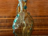 un vase en verre posé sur une table, avec un mur en bois en arrière-plan