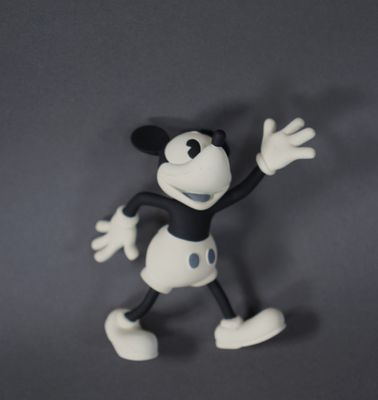 figurine de mickey mouse sur une surface grise avec un fond gris