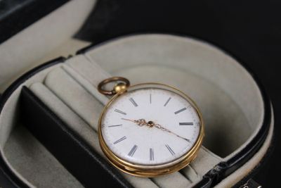 a gold pocket watch sitting in a case on a table
