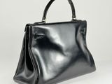 a black leather handbag with a metal handle on a white background