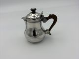 a small silver tea pot with a wooden handle on a white surface