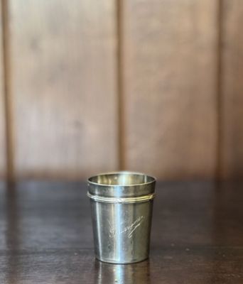 une petite tasse en métal posée sur une table en bois