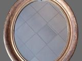 a close up of a round mirror on a gray wall