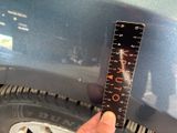a hand that is holding a ruler in front of a car