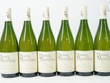 six bouteilles de vin sont alignées sur une surface blanche