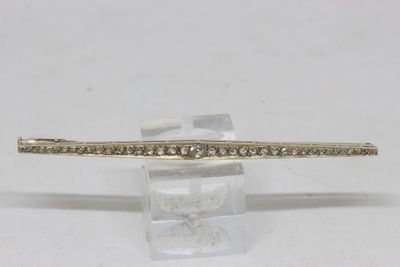 a close up of a gold and diamond bracelet on a clear stand