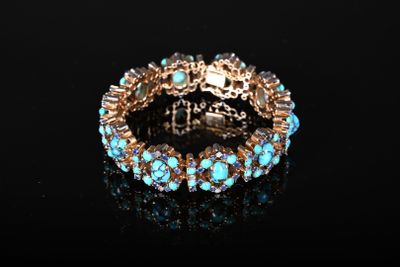 un gros plan d'un bracelet orné de pierres turquoise sur un fond noir
