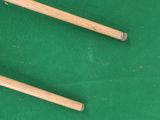 two wooden chopsticks on a green surface