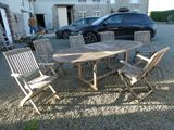 une table et des chaises en bois sur un terrain recouvert de gravier