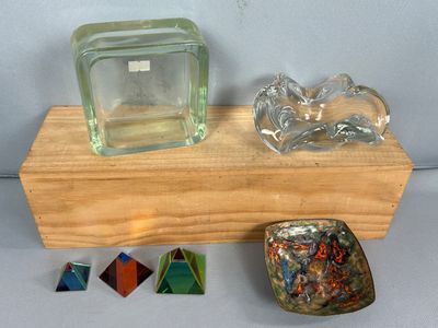 un bloc de verre posé sur un socle en bois, à côté d'autres objets en verre
