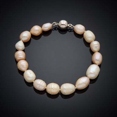 a white pearl bracelet with a silver clasp on a black background