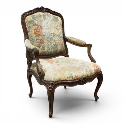 une vieille chaise dont l'assise est recouverte d'un tissu à motifs floraux