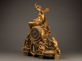 a gold clock with a woman sitting on top of it