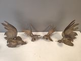 four bronze birds on a white table with a gray background
