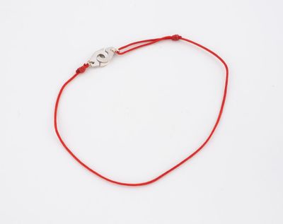 un bracelet en fil rouge orné d'un pendentif « œil maléfique » sur fond blanc