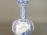 a blue and white vase with a mountain scene on it