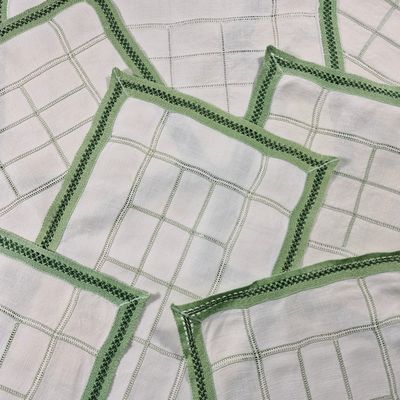 de nombreuses serviettes blanches bordées de vert sur une table