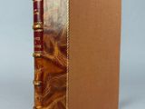 un livre marron à la couverture dorée, avec un marque-page rouge