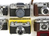 plusieurs vieux appareils photo sont alignés sur une surface blanche