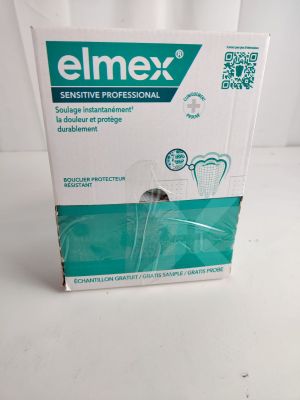 une boîte vide contenant une brosse à dents, posée sur une surface blanche