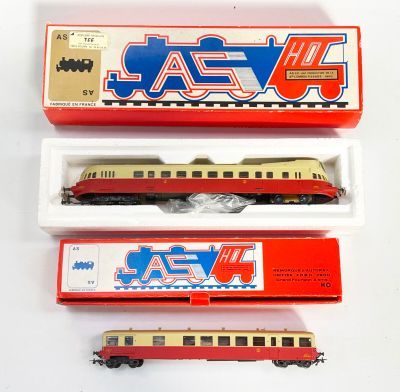 Trois petits trains sont posés dans une boîte sur une surface blanche.