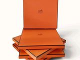trois boîtes orange sont empilées les unes sur les autres sur une surface blanche
