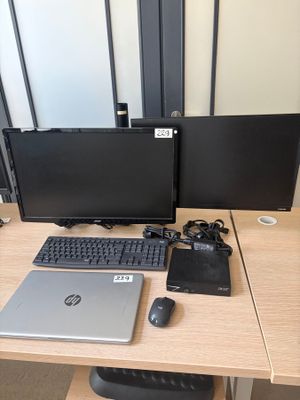 a desk with two monitors, a laptop, a mouse, and a keyboard