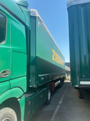 a green semi truck parked next to a green semi truck