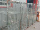 many cages in front of a building that have birds in them