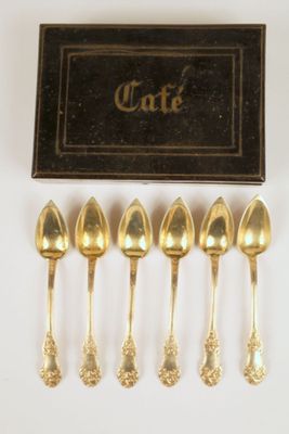 six cuillères en or dans une boîte, avec une boîte noire en arrière-plan