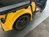 a yellow golf cart parked in a garage with its door open