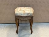 un petit tabouret dont l'assise est recouverte d'un tissu à motifs floraux